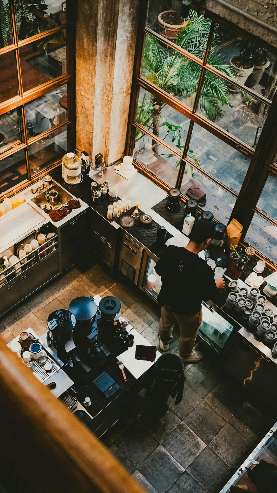 Overhead view of a barista working beside a sunlit window in a Da Nang cafe