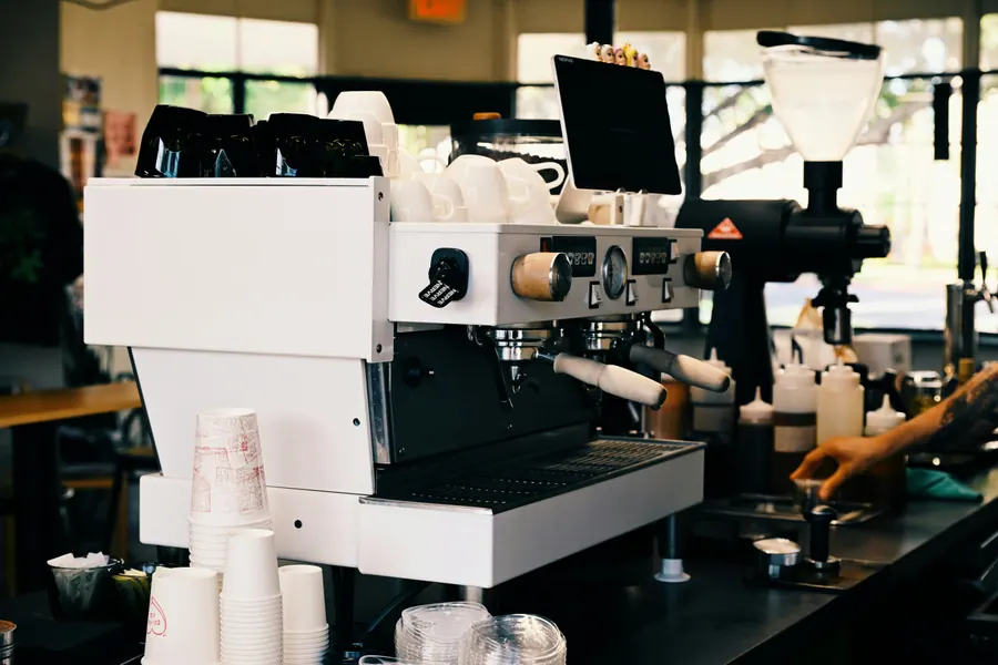 Espresso machine and grinder at a cafe counter with a barista preparing a drink